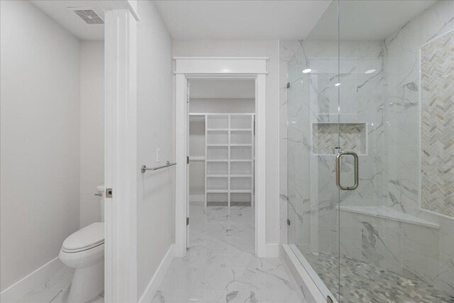 bathroom featuring a shower with shower door and toilet