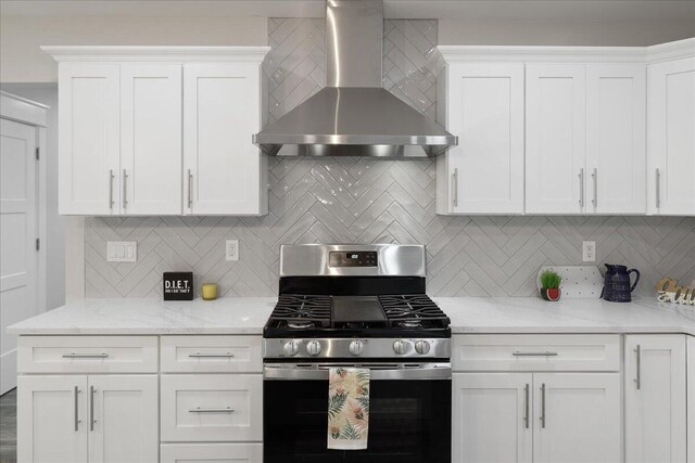 kitchen featuring white cabinets, decorative backsplash, wall chimney range hood, and gas range