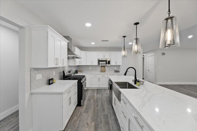 kitchen featuring dark wood-type flooring, wall chimney range hood, pendant lighting, white cabinets, and appliances with stainless steel finishes