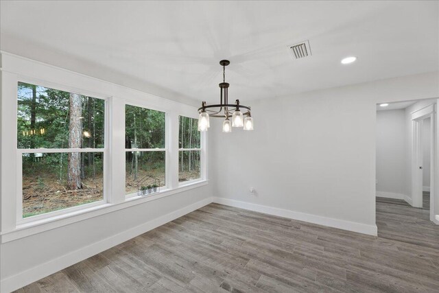 unfurnished dining area featuring wood-type flooring and a notable chandelier