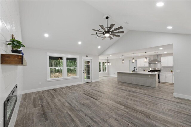 unfurnished living room featuring ceiling fan, sink, high vaulted ceiling, and hardwood / wood-style flooring