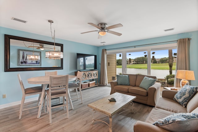 living room featuring ceiling fan with notable chandelier and hardwood / wood-style flooring