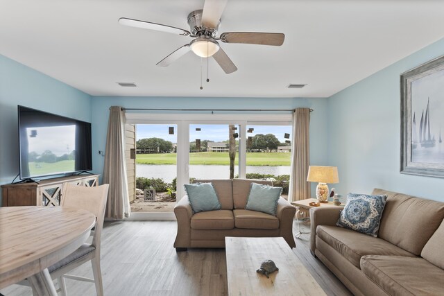 living room featuring light hardwood / wood-style flooring, a water view, and ceiling fan