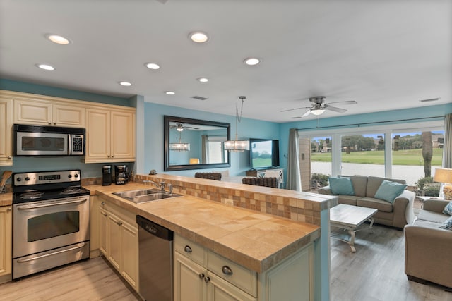 kitchen featuring light hardwood / wood-style flooring, kitchen peninsula, decorative light fixtures, and stainless steel appliances