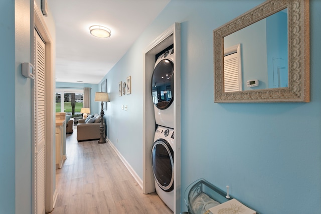 corridor with light hardwood / wood-style floors and stacked washer and clothes dryer