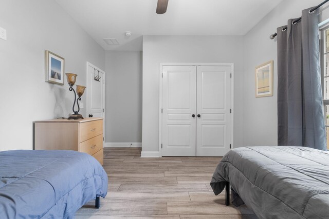 bedroom featuring light hardwood / wood-style flooring, ceiling fan, and a closet