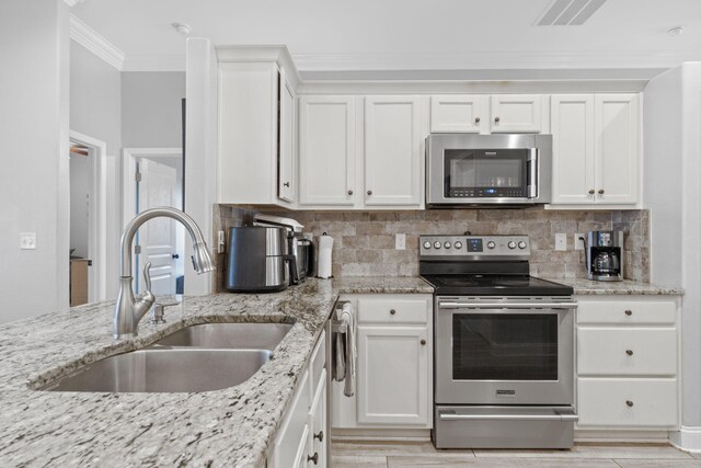 kitchen with light hardwood / wood-style flooring, appliances with stainless steel finishes, sink, white cabinetry, and light stone counters