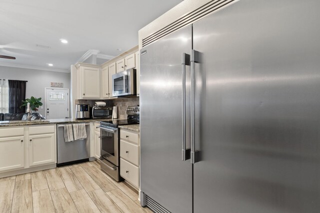 kitchen with stone counters, light hardwood / wood-style flooring, ceiling fan, decorative backsplash, and appliances with stainless steel finishes