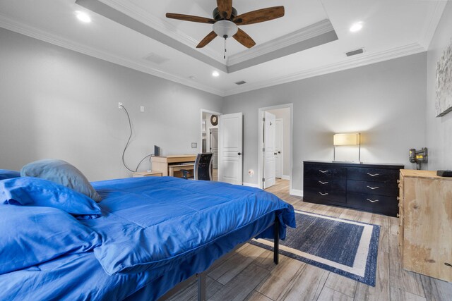 bedroom featuring hardwood / wood-style floors, ceiling fan, a tray ceiling, and ornamental molding