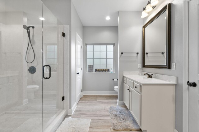 bathroom featuring vanity, toilet, hardwood / wood-style flooring, and a shower with door