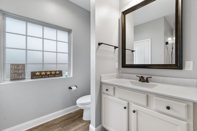 bathroom with a wealth of natural light, vanity, toilet, and hardwood / wood-style flooring