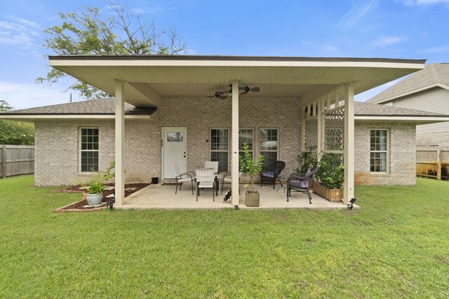 rear view of property featuring ceiling fan, a lawn, and a patio area