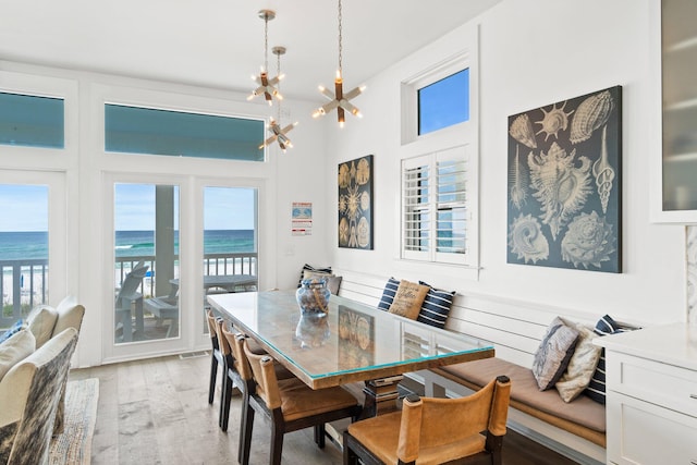 dining area with a water view, a chandelier, and light hardwood / wood-style floors