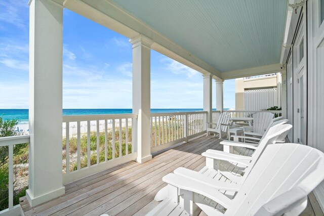 wooden deck featuring a water view and a view of the beach