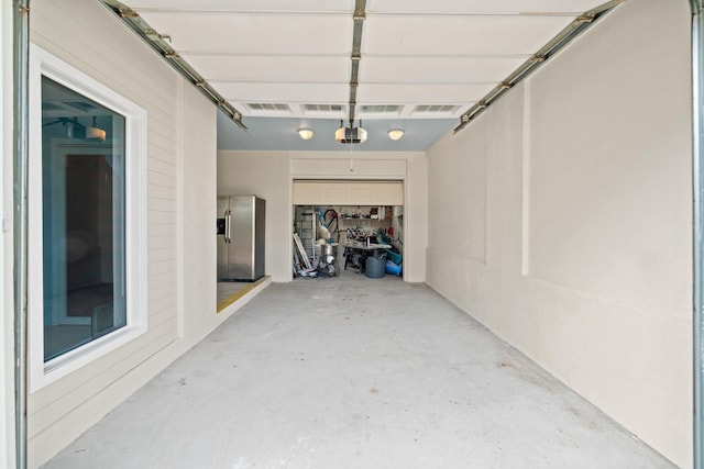 garage featuring a garage door opener and stainless steel fridge with ice dispenser