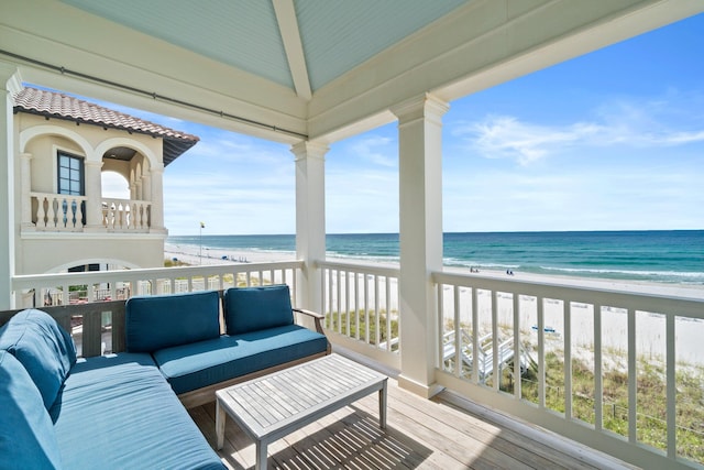 balcony with an outdoor living space, a beach view, and a water view