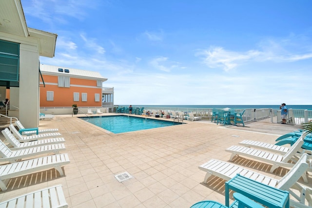 view of swimming pool featuring a water view and a patio