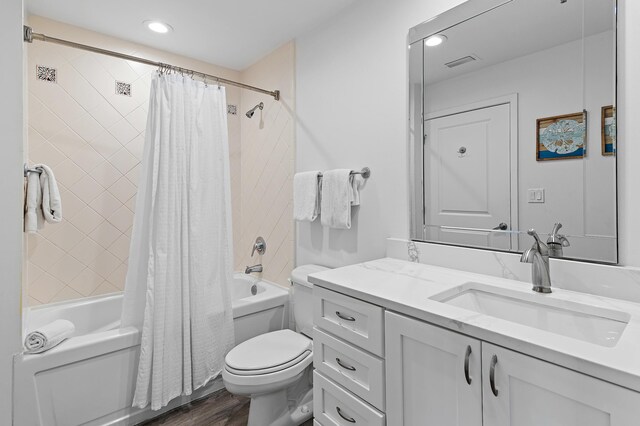 full bathroom with wood-type flooring, shower / tub combo with curtain, vanity, and toilet