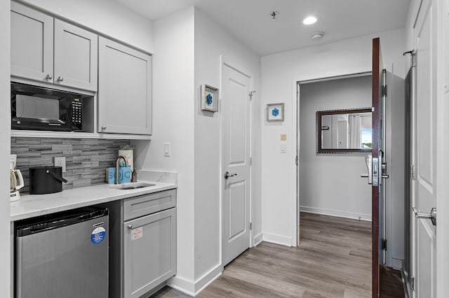 kitchen with sink, light hardwood / wood-style flooring, dishwasher, gray cabinets, and light stone countertops