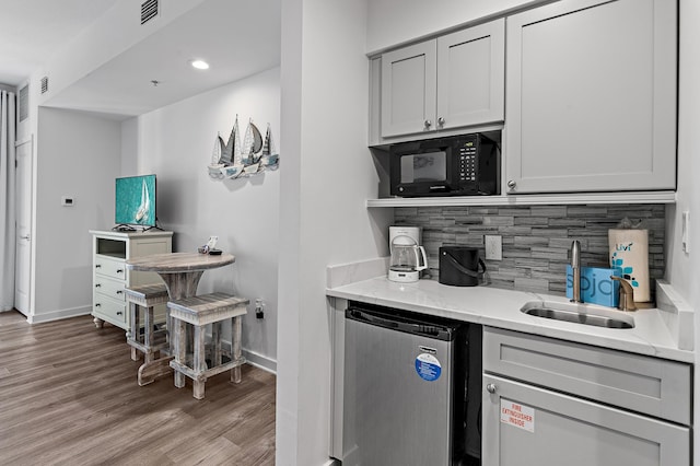 kitchen with gray cabinets, light hardwood / wood-style floors, sink, backsplash, and stainless steel fridge