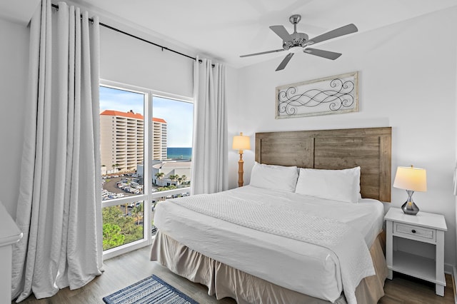 bedroom featuring a water view, ceiling fan, and hardwood / wood-style flooring