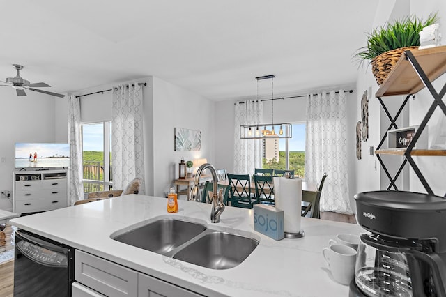 kitchen featuring decorative light fixtures, light hardwood / wood-style flooring, black dishwasher, and a wealth of natural light