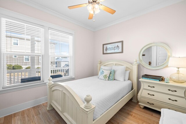 bedroom featuring multiple windows, ornamental molding, light wood-type flooring, and ceiling fan