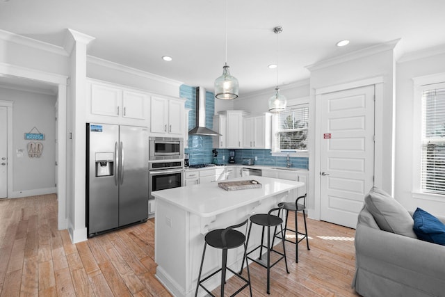 kitchen with light hardwood / wood-style floors, white cabinetry, built in appliances, sink, and wall chimney range hood