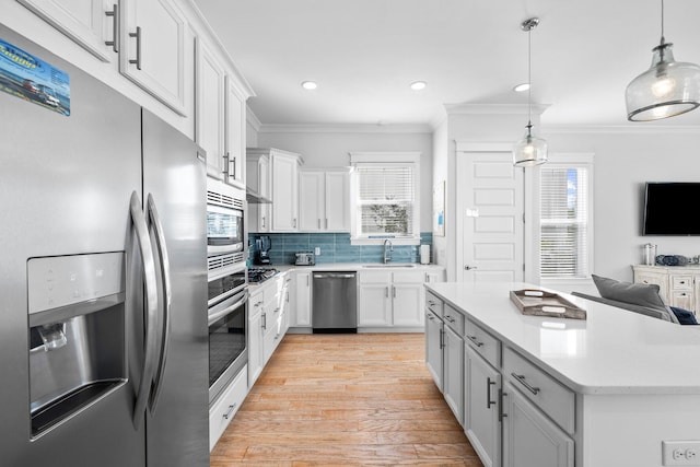 kitchen with light hardwood / wood-style flooring, stainless steel appliances, hanging light fixtures, and white cabinetry