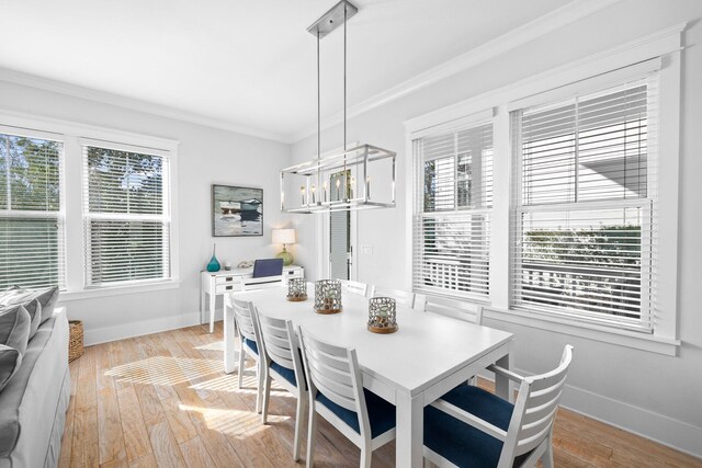 dining area with a notable chandelier, light hardwood / wood-style flooring, ornamental molding, and a healthy amount of sunlight