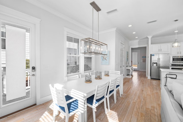 dining area with a notable chandelier, light wood-type flooring, and crown molding