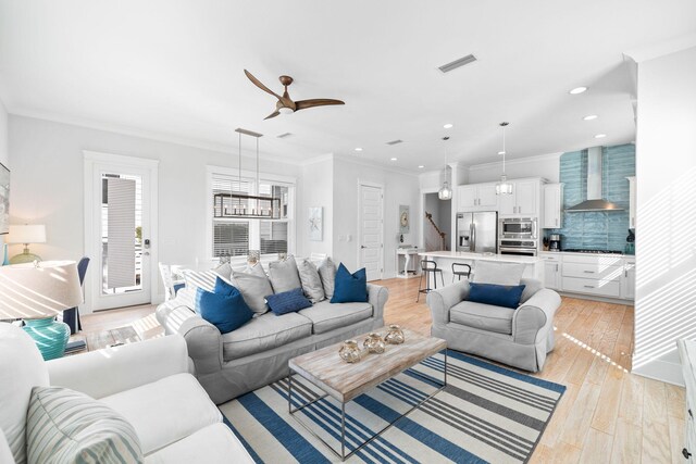 living room with light wood-type flooring, crown molding, and ceiling fan