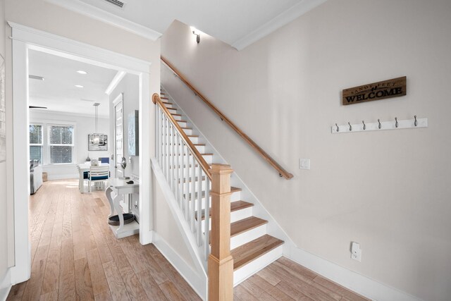 stairs with wood-type flooring and ornamental molding