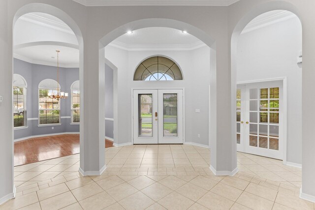 entrance foyer featuring ornamental molding, french doors, light hardwood / wood-style flooring, and a notable chandelier