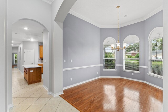 unfurnished room featuring a chandelier, crown molding, and light hardwood / wood-style flooring