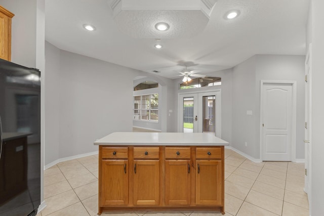 kitchen with black fridge, ceiling fan, a center island, and a textured ceiling