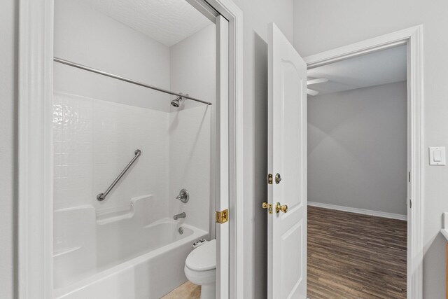 bathroom featuring a textured ceiling, toilet, shower / bath combination, and wood-type flooring