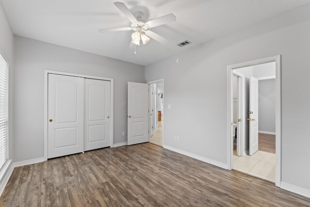 unfurnished bedroom with a textured ceiling, ceiling fan, a closet, and hardwood / wood-style flooring