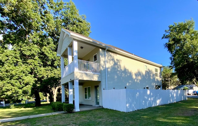 view of side of property featuring a yard and a balcony