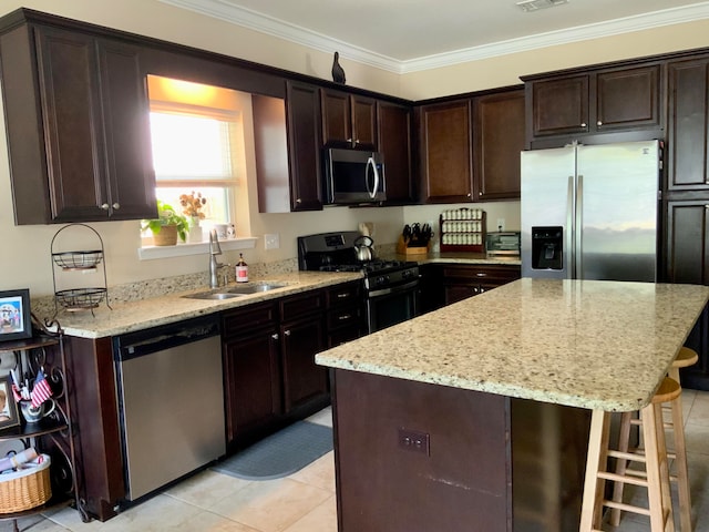 kitchen with sink, appliances with stainless steel finishes, dark brown cabinets, crown molding, and a kitchen island