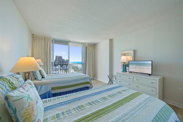 bedroom with a textured ceiling, light hardwood / wood-style flooring, and access to exterior