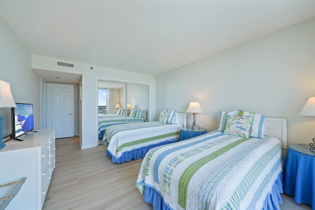 bedroom with a closet, a textured ceiling, and light wood-type flooring