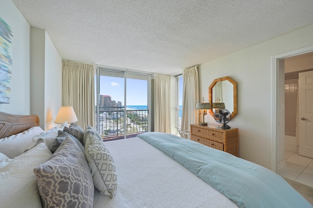 bedroom featuring a wall of windows, light tile patterned flooring, a textured ceiling, and access to outside