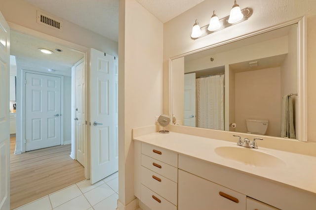 bathroom with toilet, a textured ceiling, vanity, and wood-type flooring