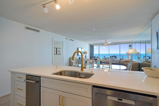 kitchen featuring dishwasher, hardwood / wood-style flooring, sink, a textured ceiling, and a water view