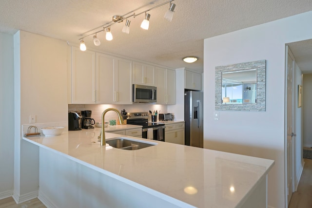 kitchen featuring kitchen peninsula, white cabinetry, stainless steel appliances, and a textured ceiling