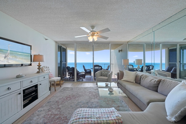 living room featuring light hardwood / wood-style flooring, a water view, and a wealth of natural light