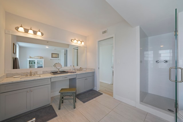 bathroom with a shower with door, vanity, and tile patterned floors