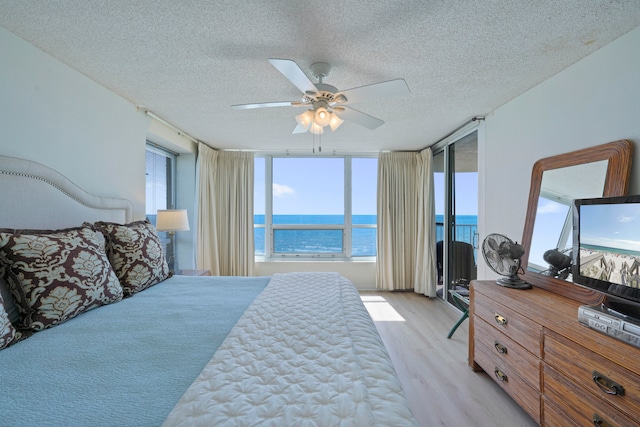 bedroom featuring ceiling fan, a textured ceiling, expansive windows, and light hardwood / wood-style floors