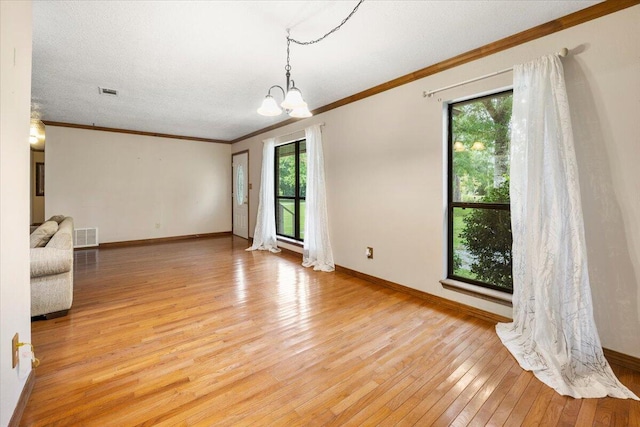 spare room featuring crown molding, a textured ceiling, a chandelier, and light hardwood / wood-style floors